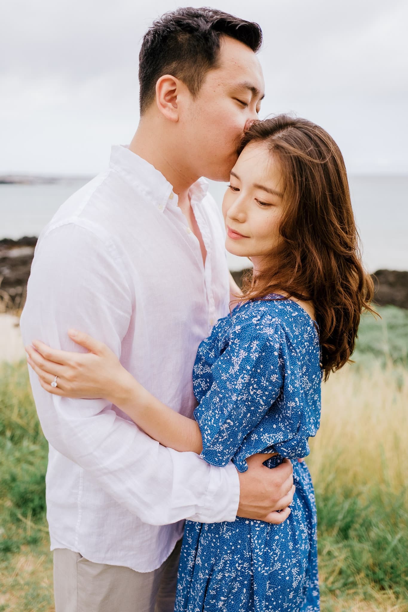 A kiss on the forehead on a grassy bluff above the sea