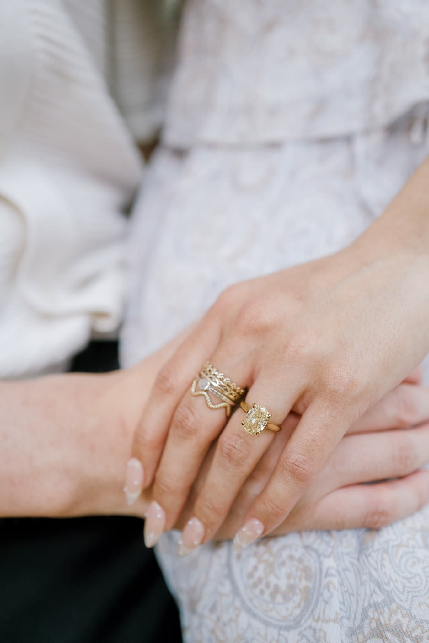 Close-up of an engagement ring on intertwined hands