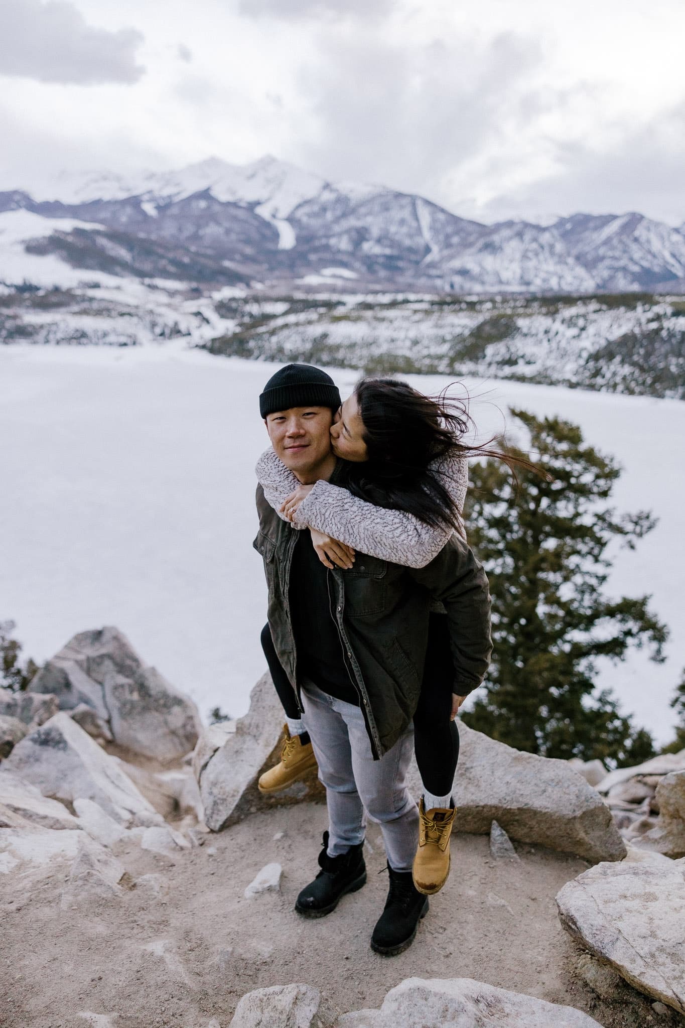 A kiss on the cheek on the rocks above a frozen lake