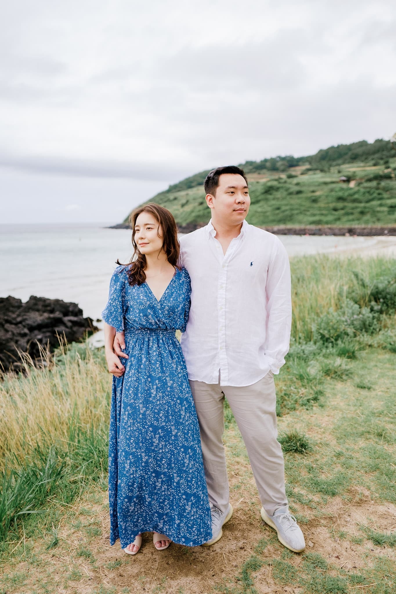 Couple standing together on a grassy bluff by the sea