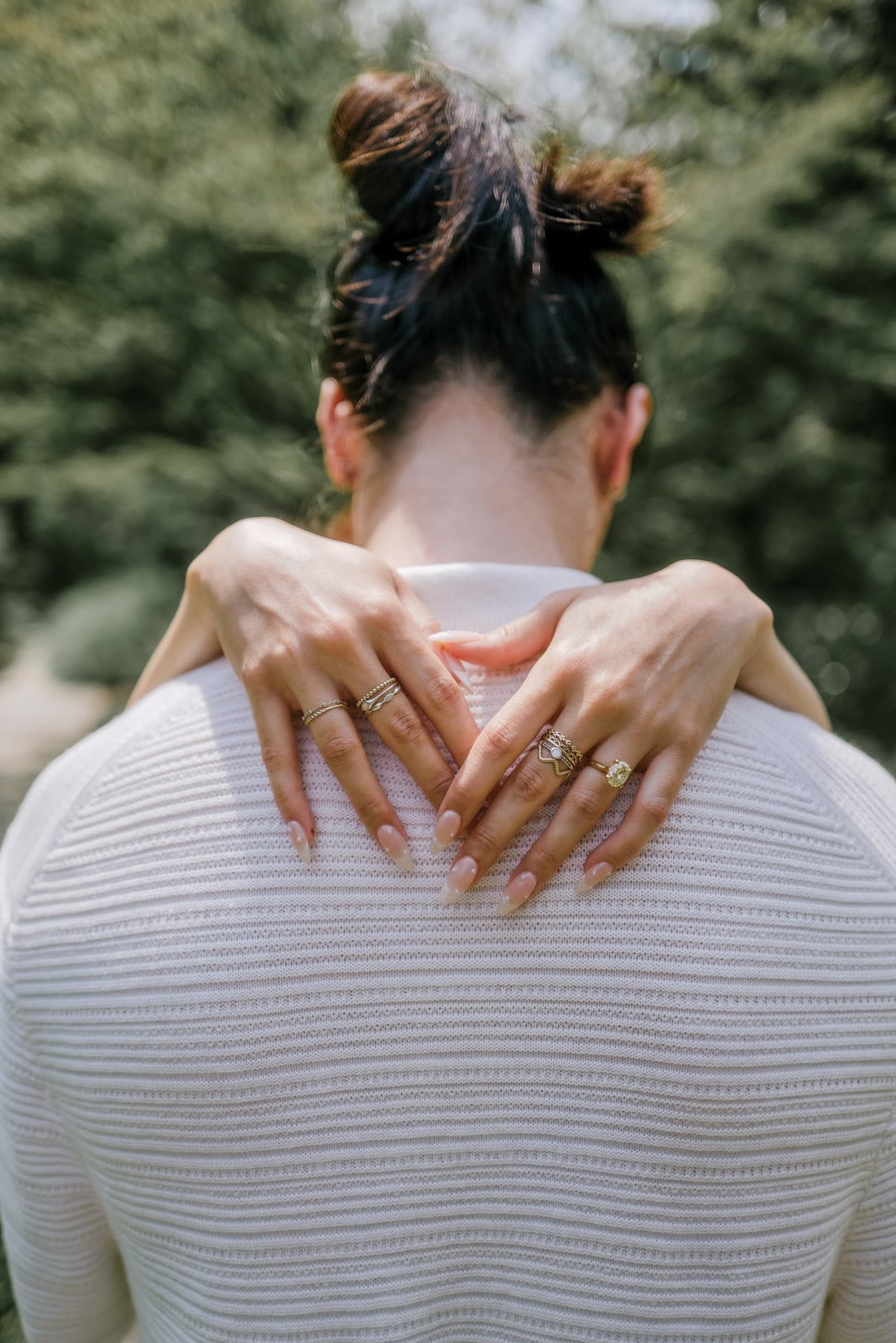 Hands with engagement rings resting on a partner’s shoulders