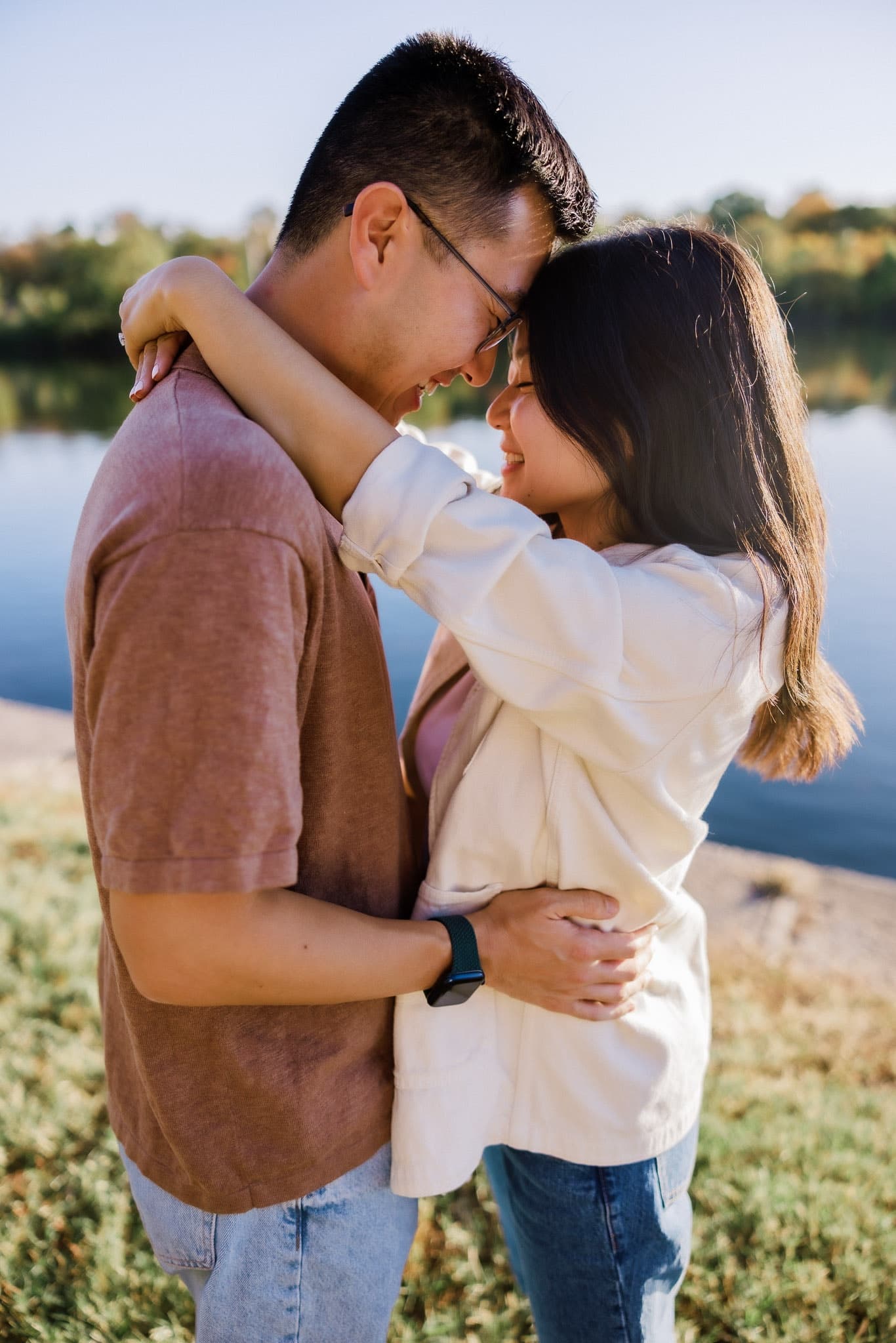 Couple resting foreheads together by the lake
