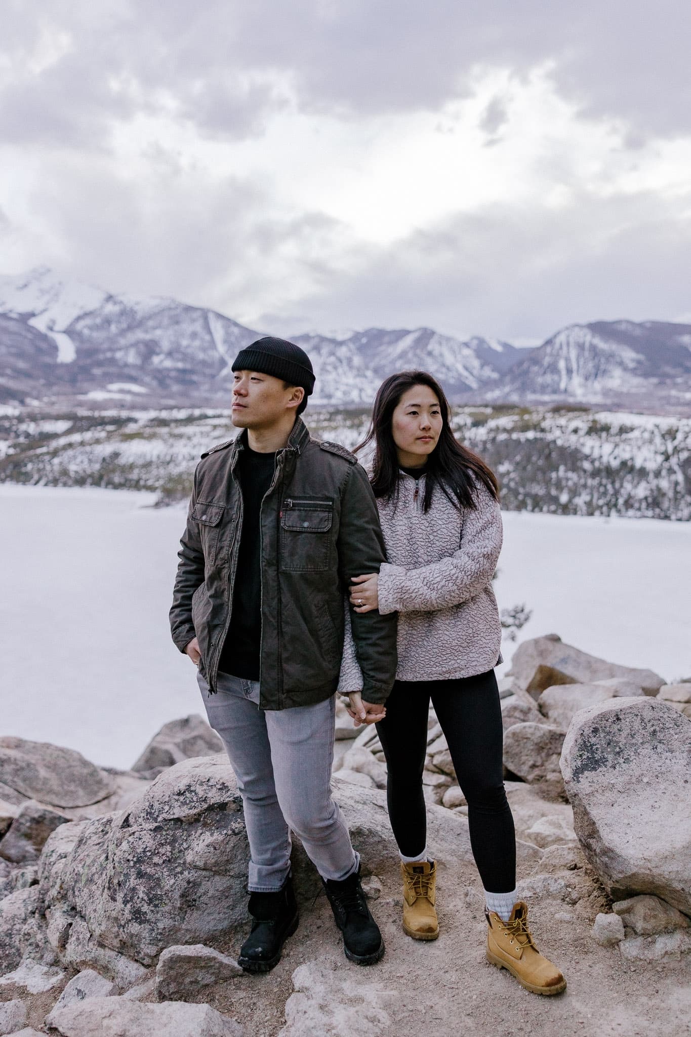Couple standing on the rocks above a frozen mountain lake