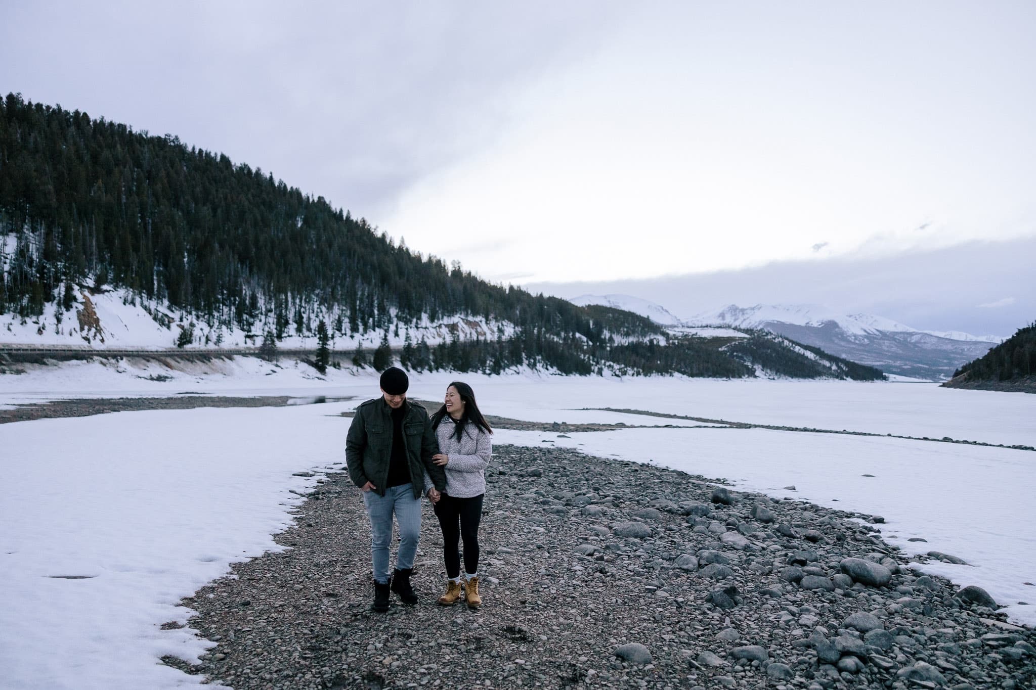 Couple walking along the shore of a snowy mountain lake