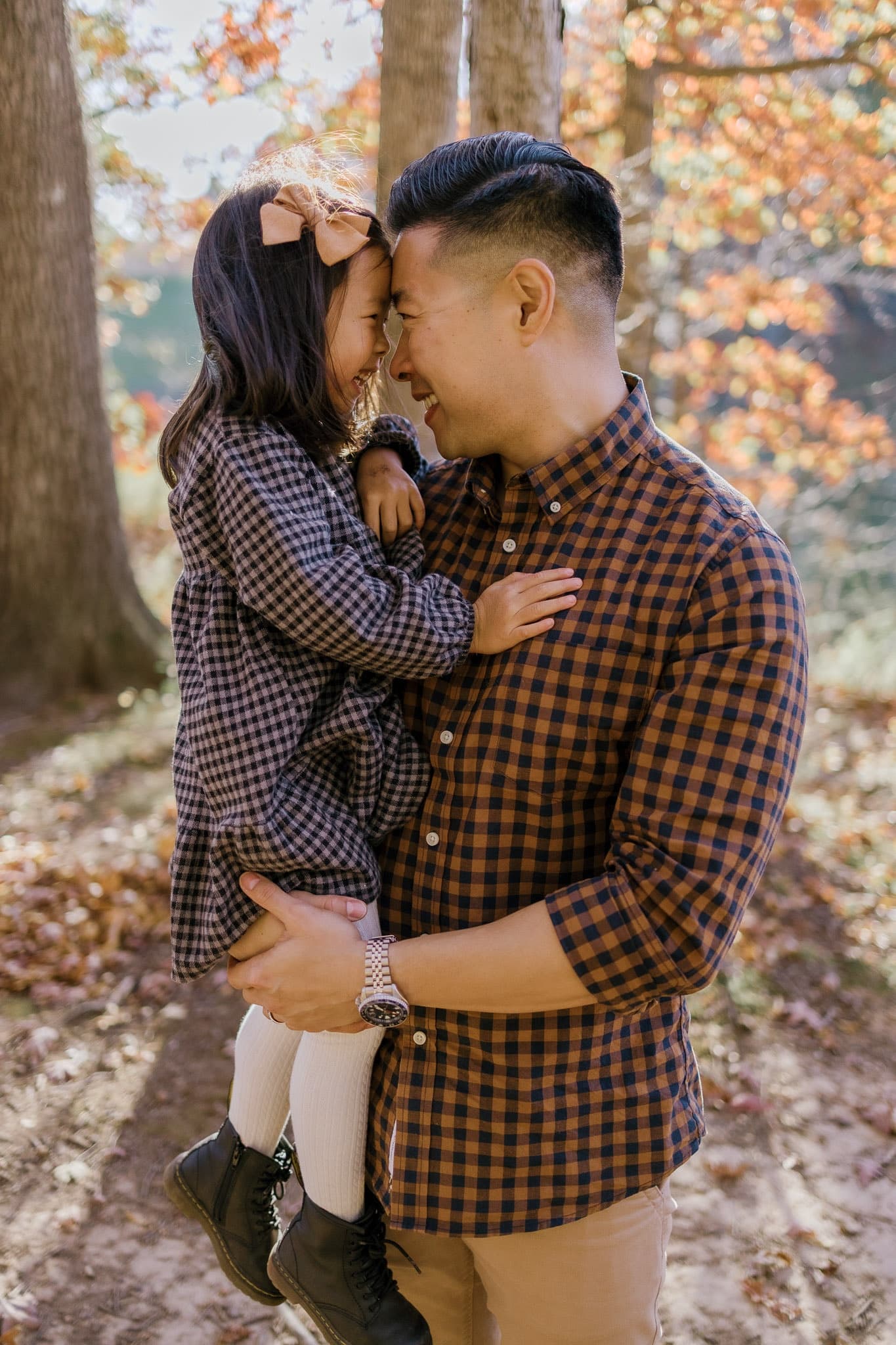 Parent and child touching foreheads among autumn trees