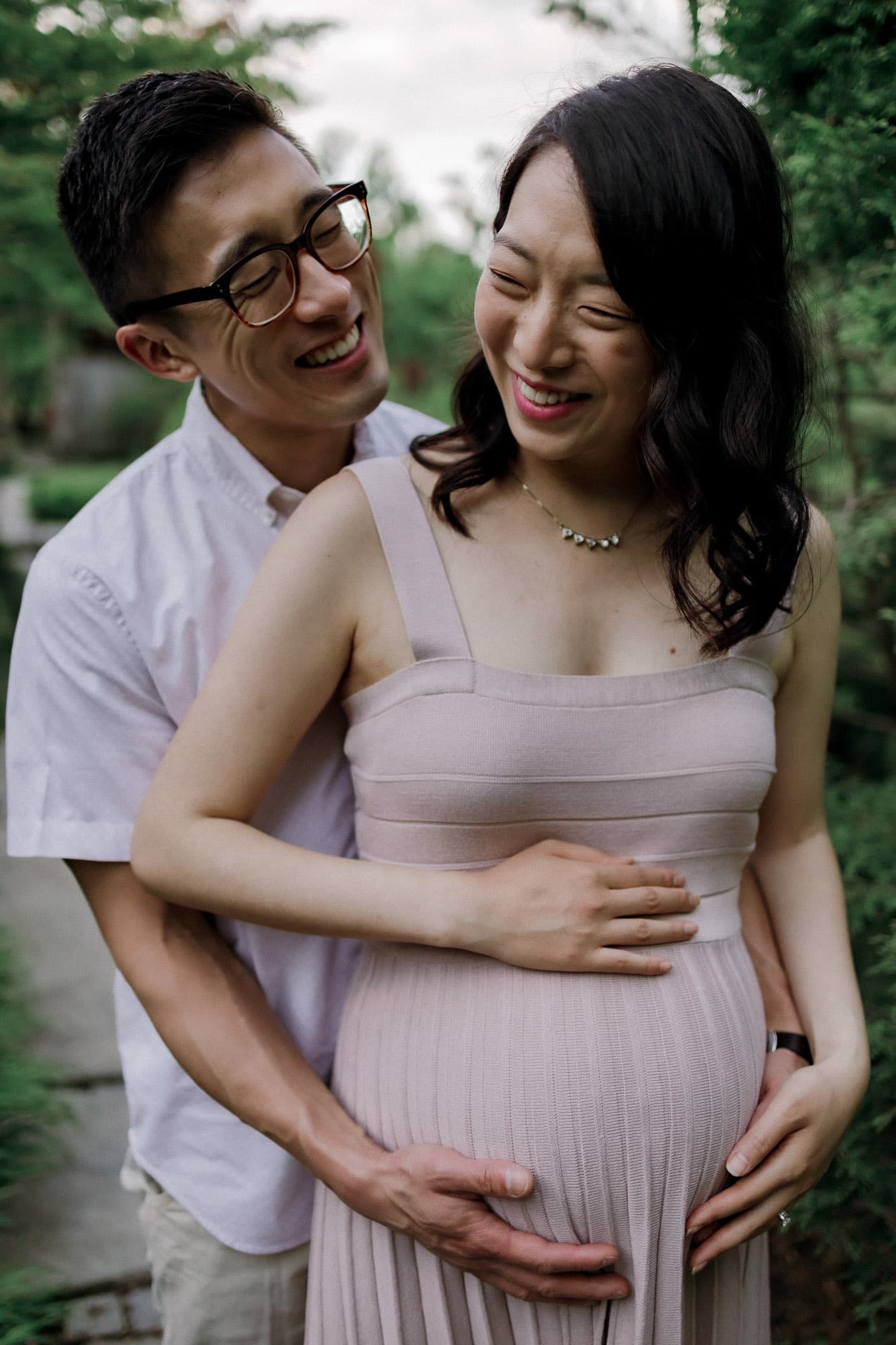 Expecting couple smiling, hands resting on the bump