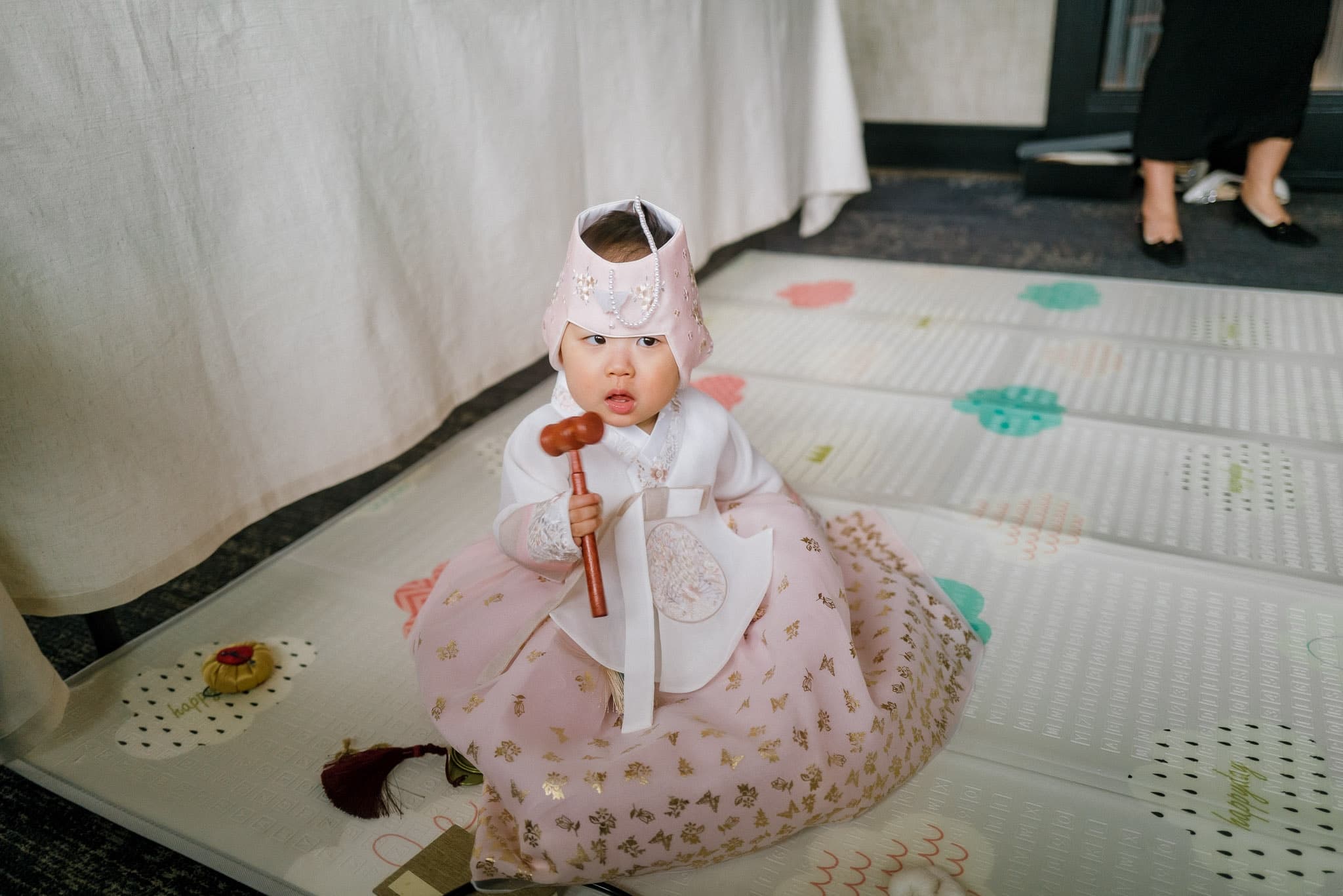 Baby in a hanbok sitting on a colorful mat