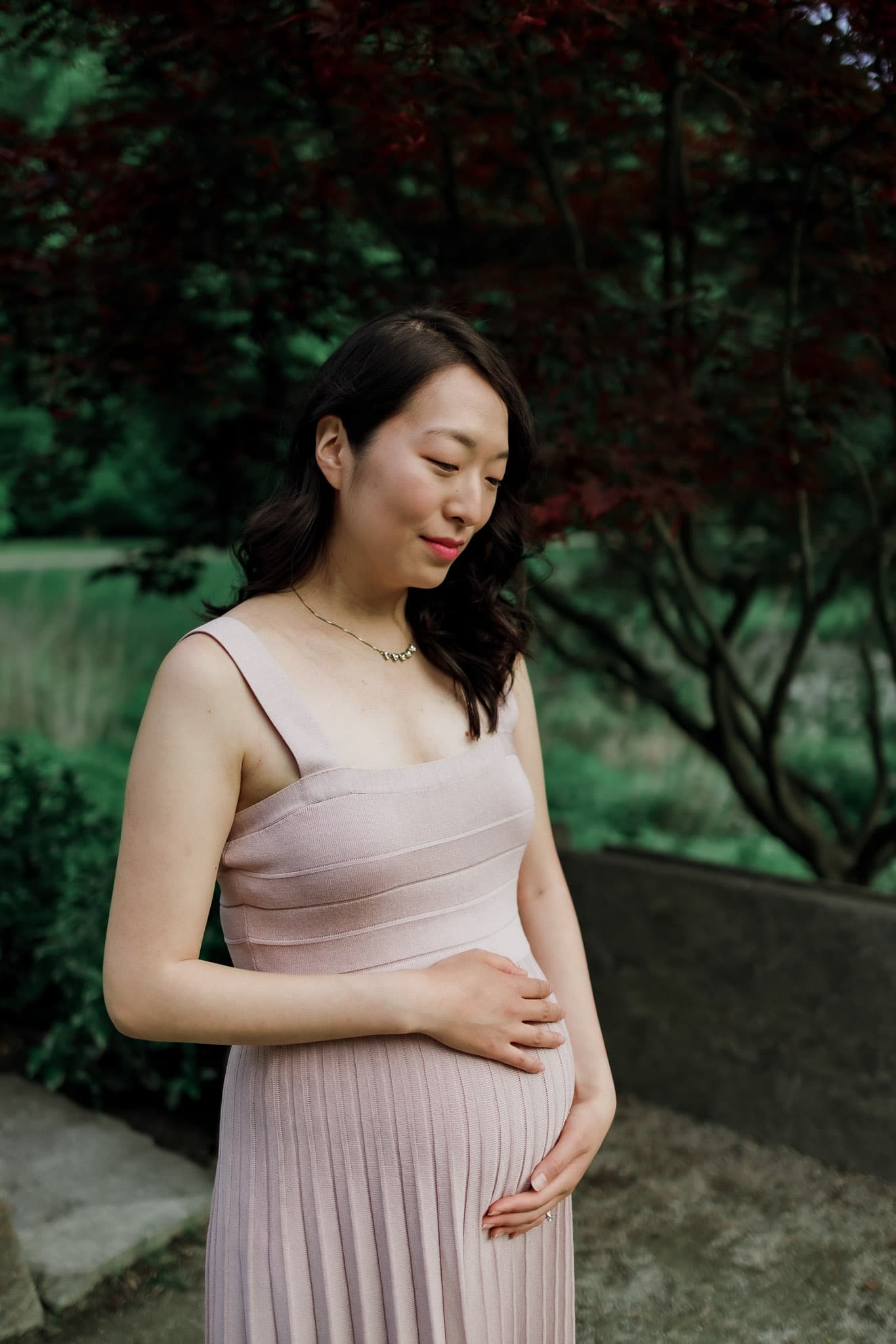 Maternity portrait in a blush dress beside the garden
