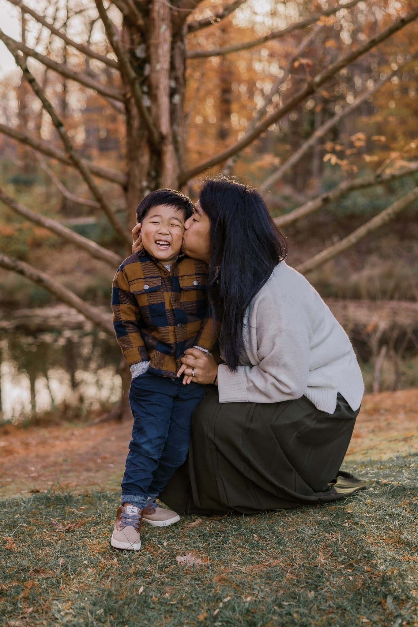 A kiss on the cheek between parent and child in autumn light