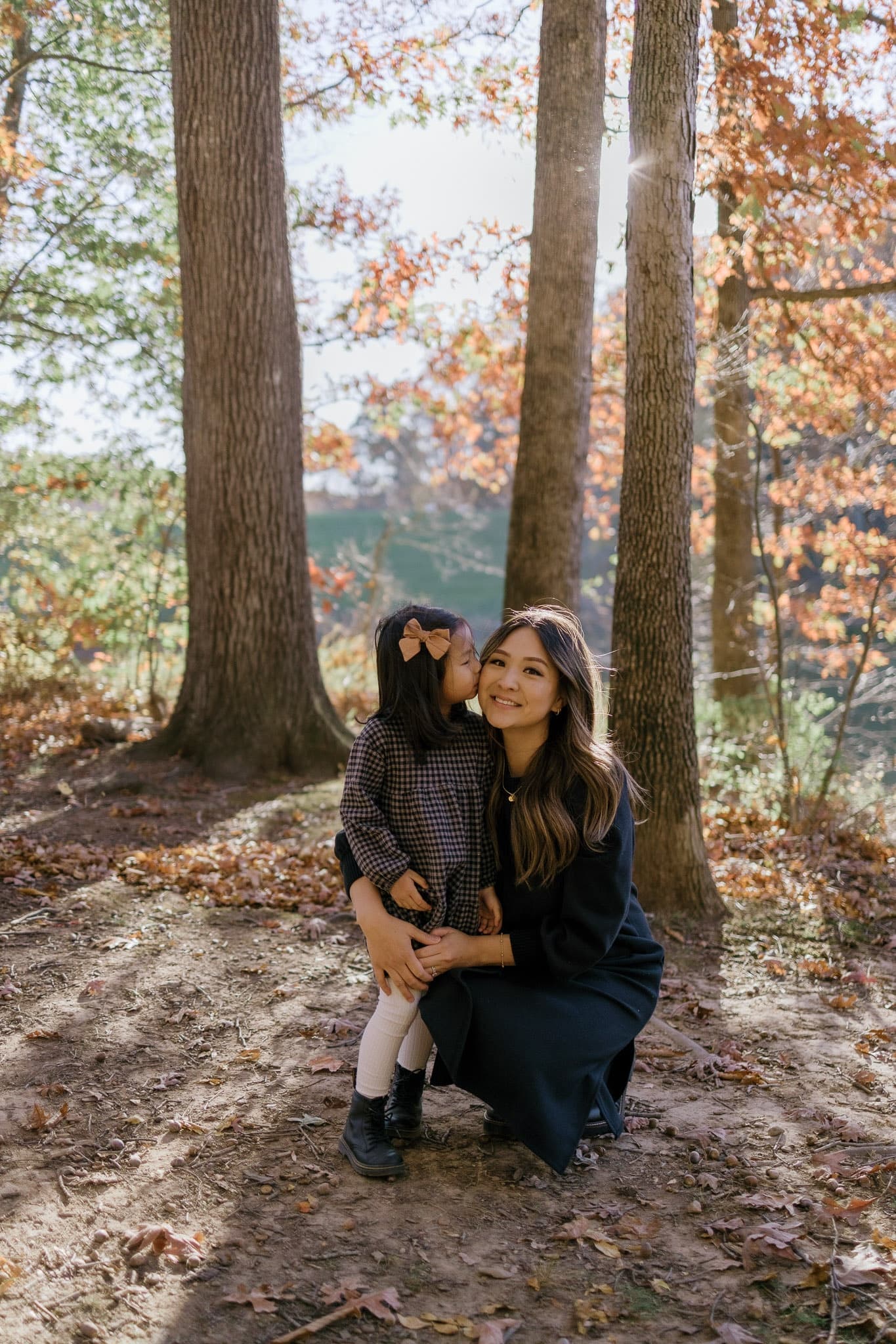Parent and child crouched together among autumn trees