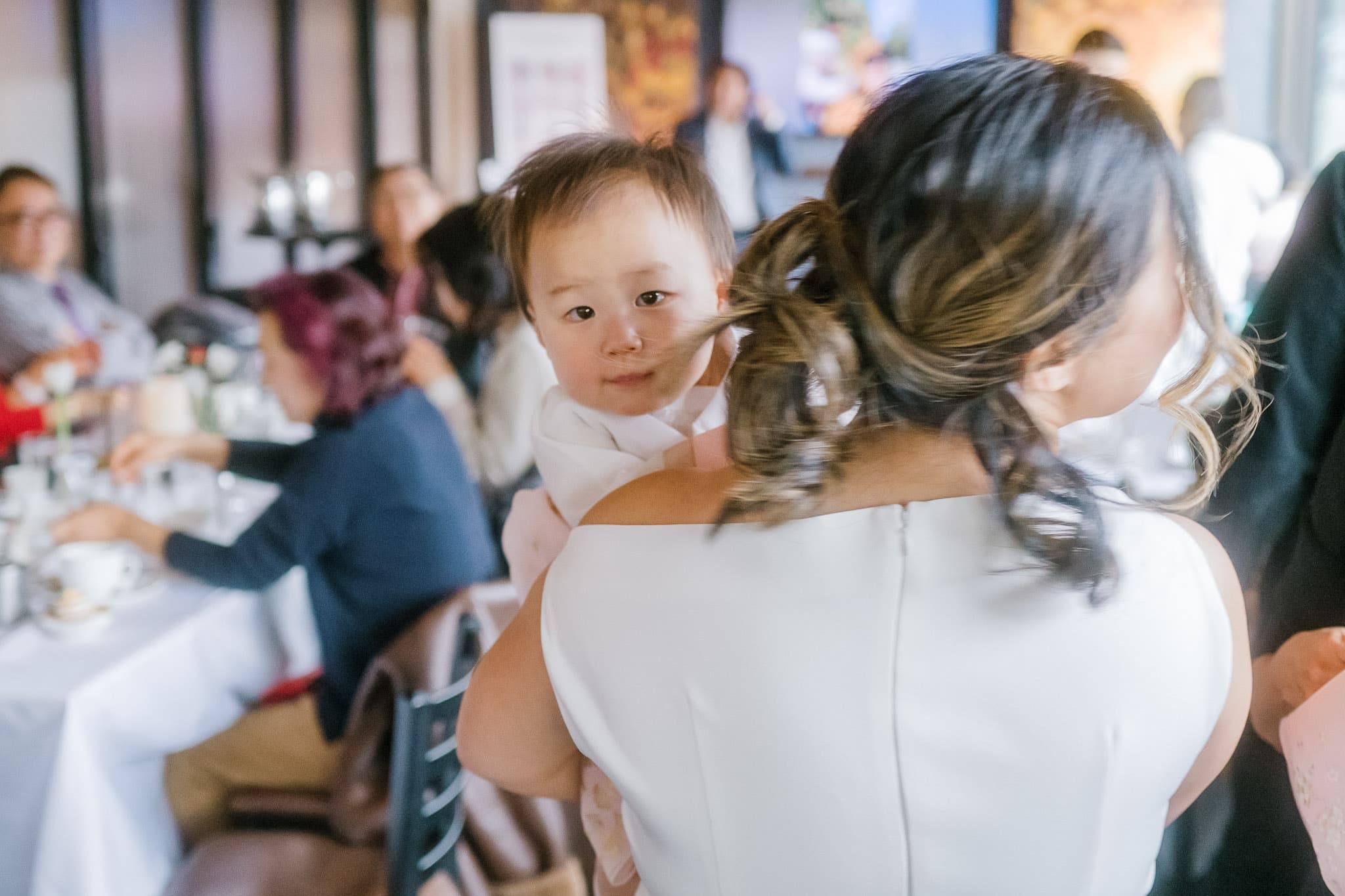 Baby peeking over a parent’s shoulder at the celebration