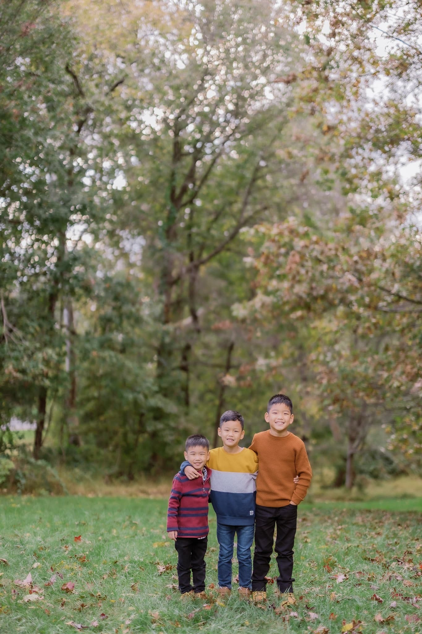 Three young siblings standing together in the park
