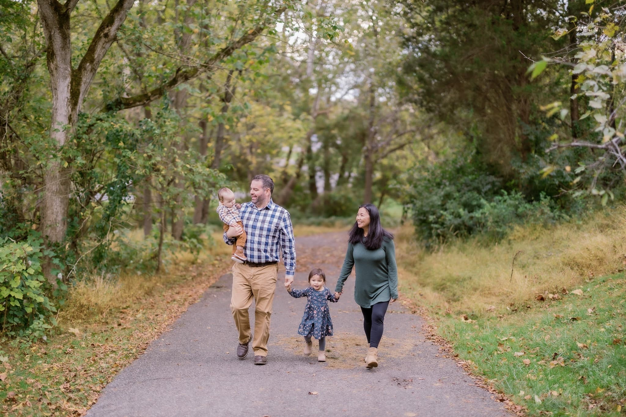 Family walking hand in hand along a park path