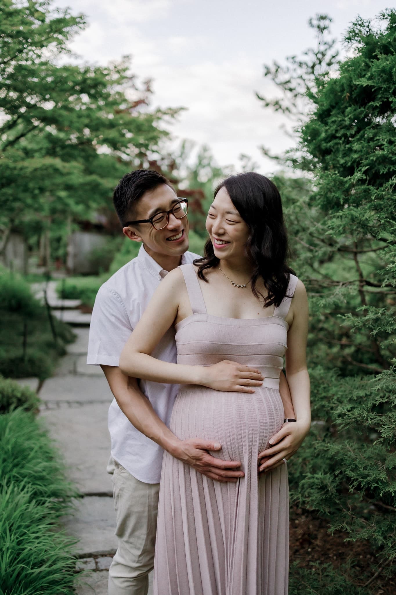 Expecting couple embracing on a garden path