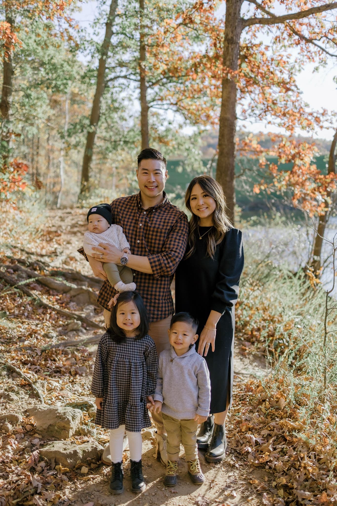 Family of five posing by the water in fall