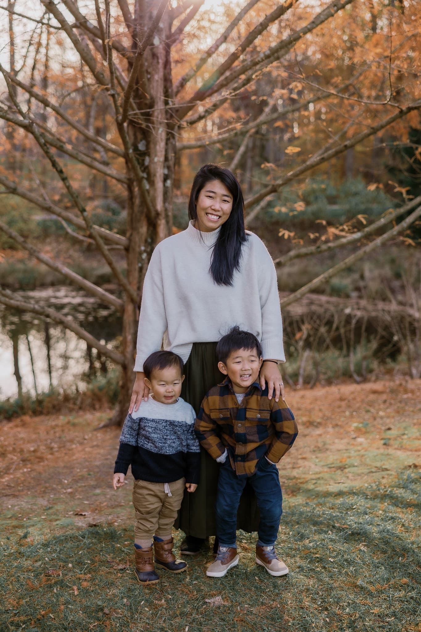 Parent standing with two young children by the pond