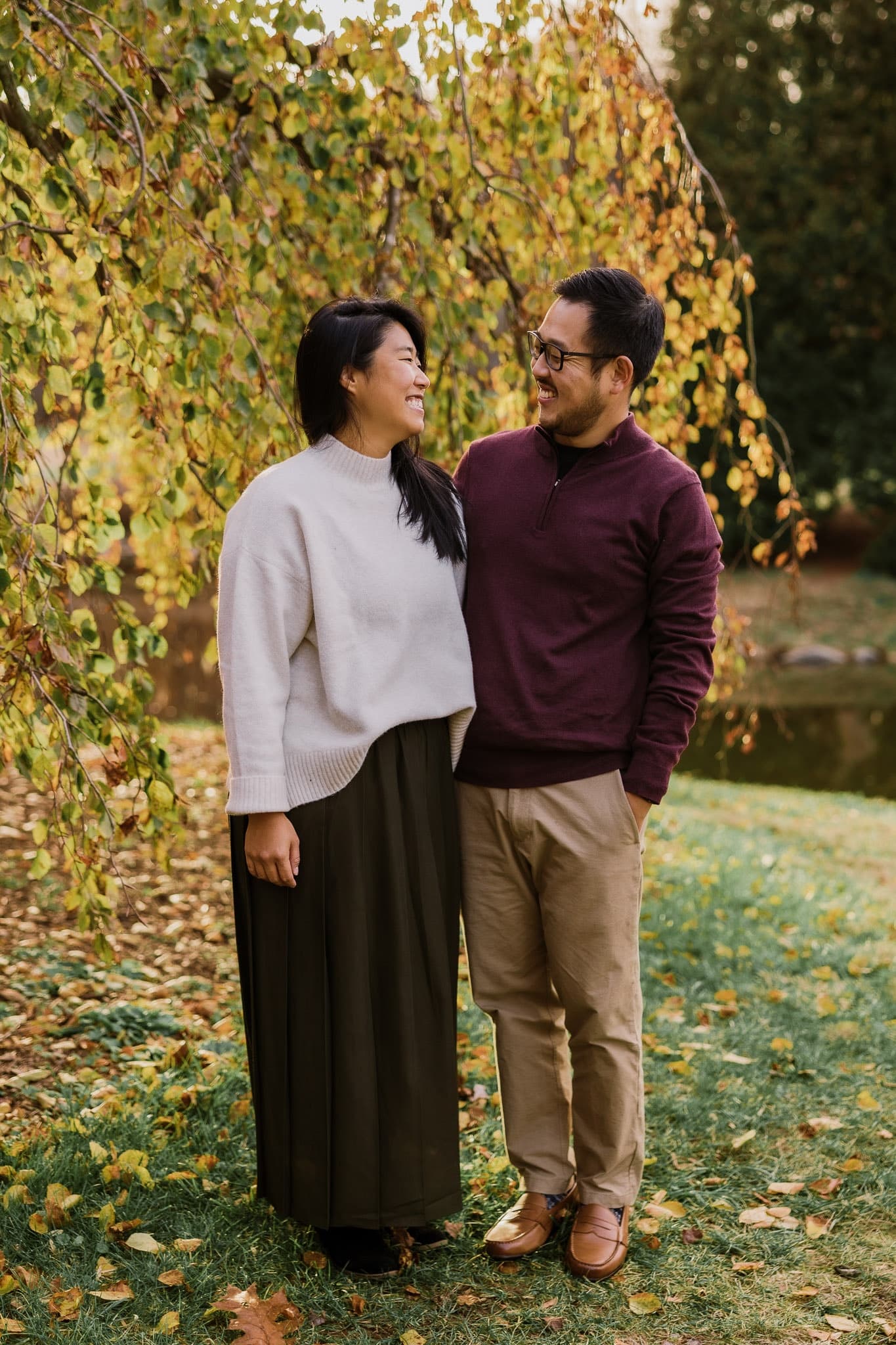 Couple smiling beneath golden autumn leaves
