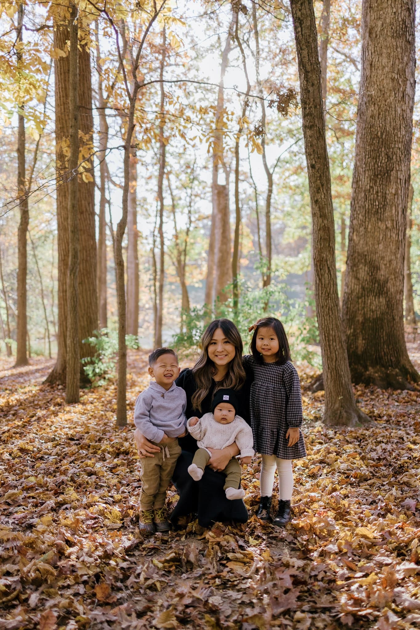 Parent kneeling with three children in the woods