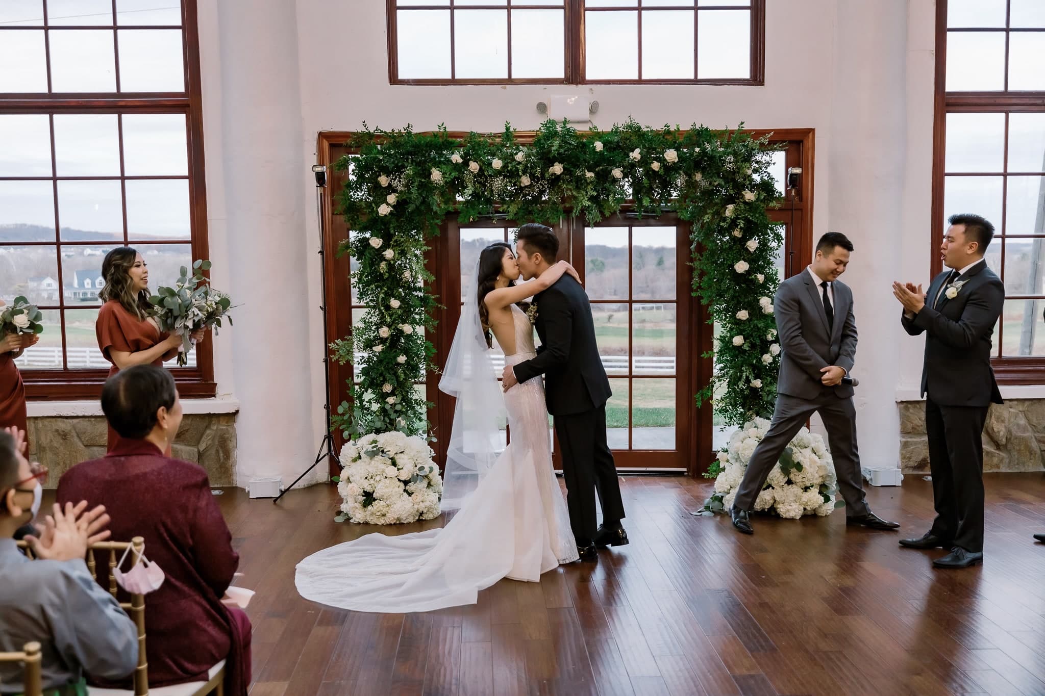 The first kiss at the altar beneath a greenery arch