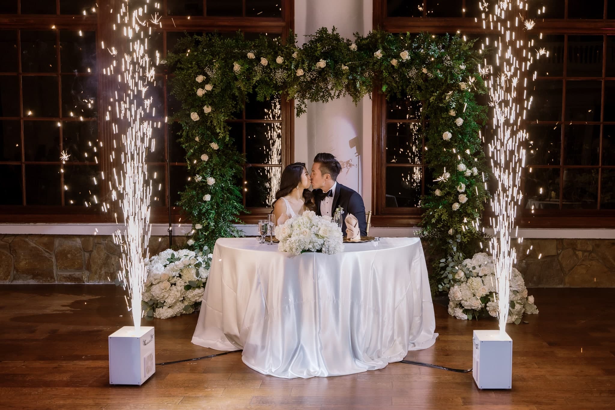 Couple at the sweetheart table between sparkler fountains