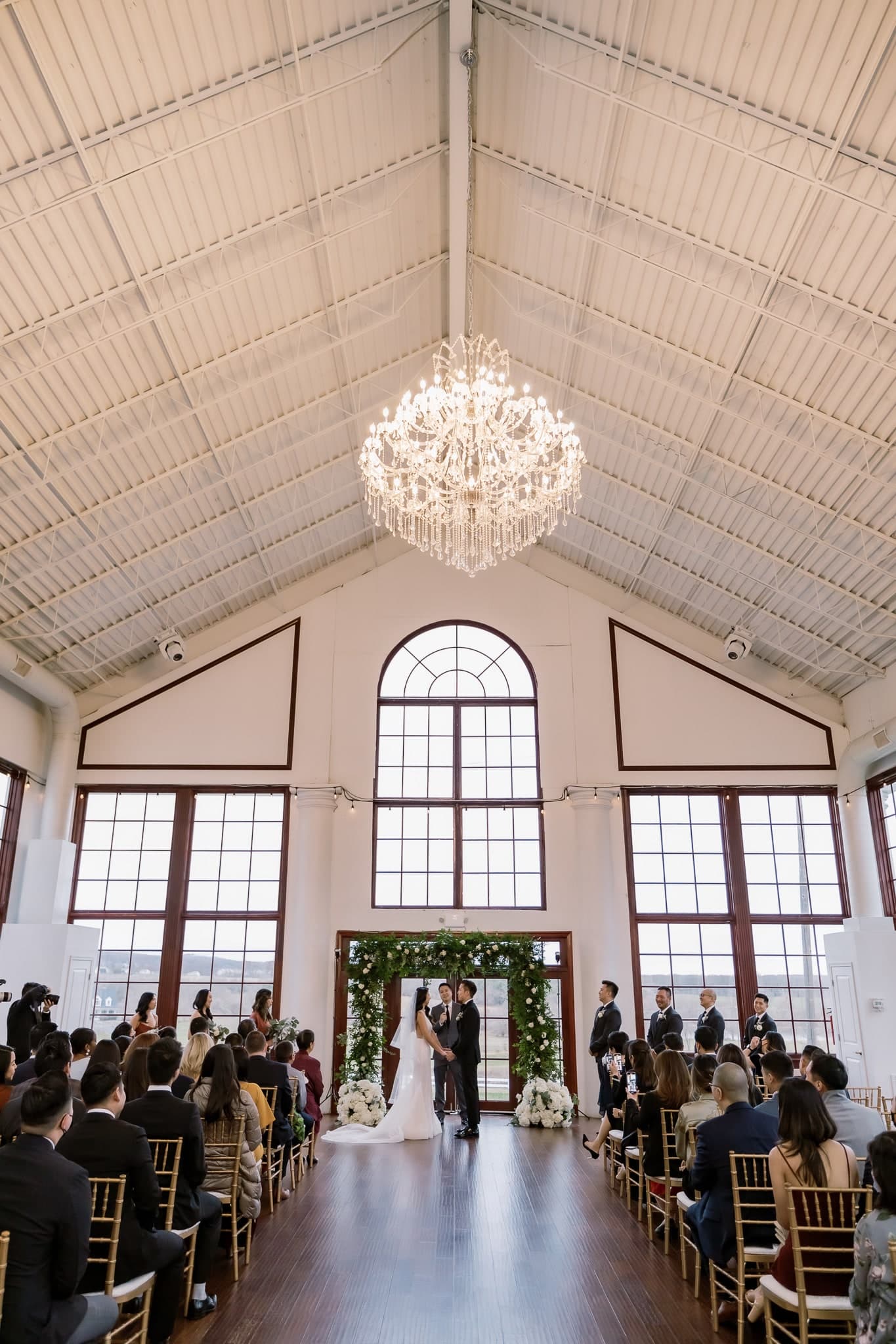 Glasshouse ceremony beneath a crystal chandelier