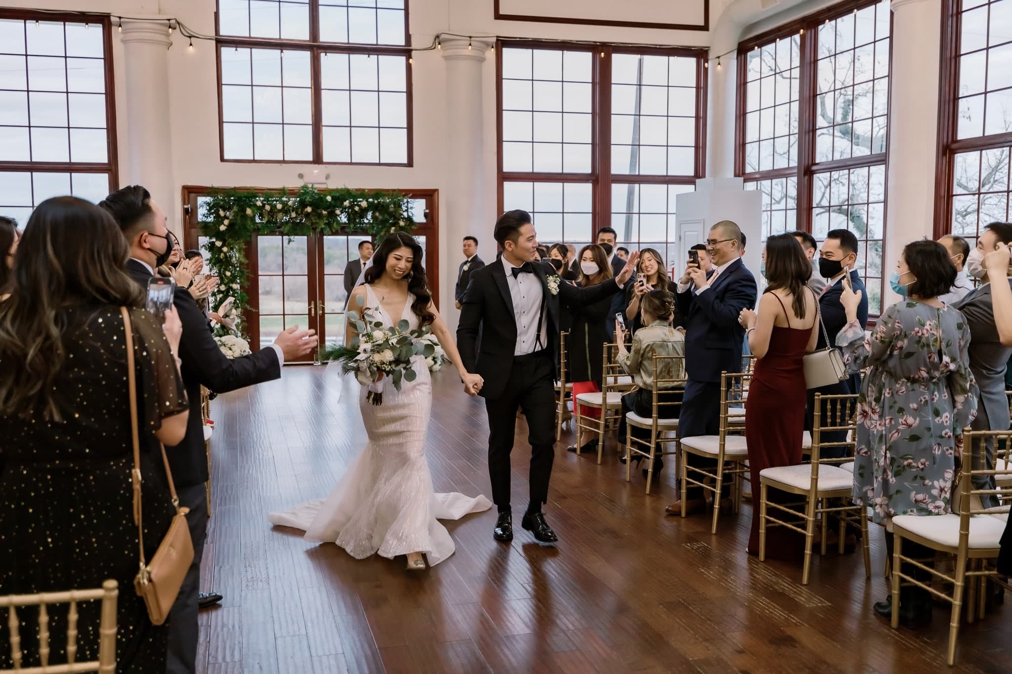 Newlyweds walking back up the aisle as guests cheer