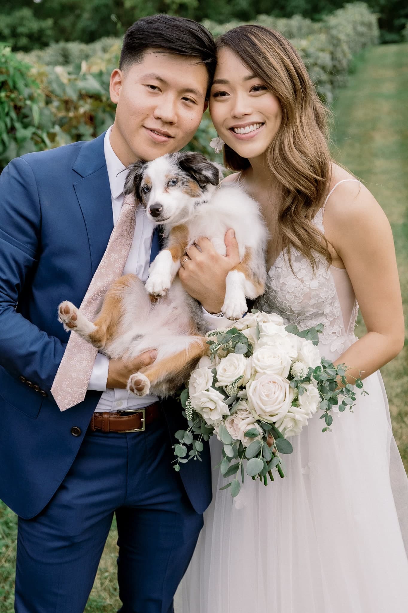 Couple smiling with their dog in the vineyard