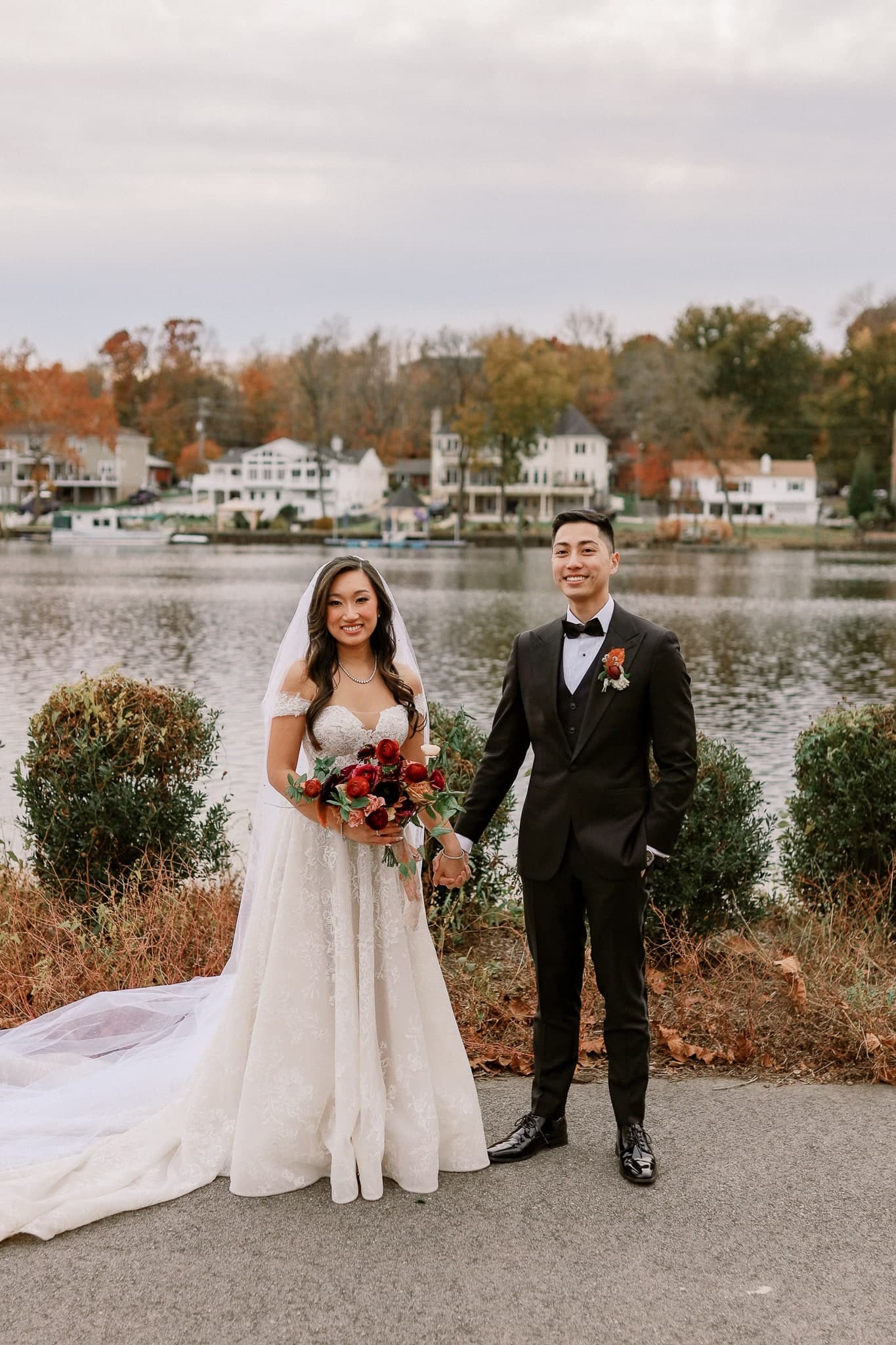 Newlyweds standing together on the lakeside path