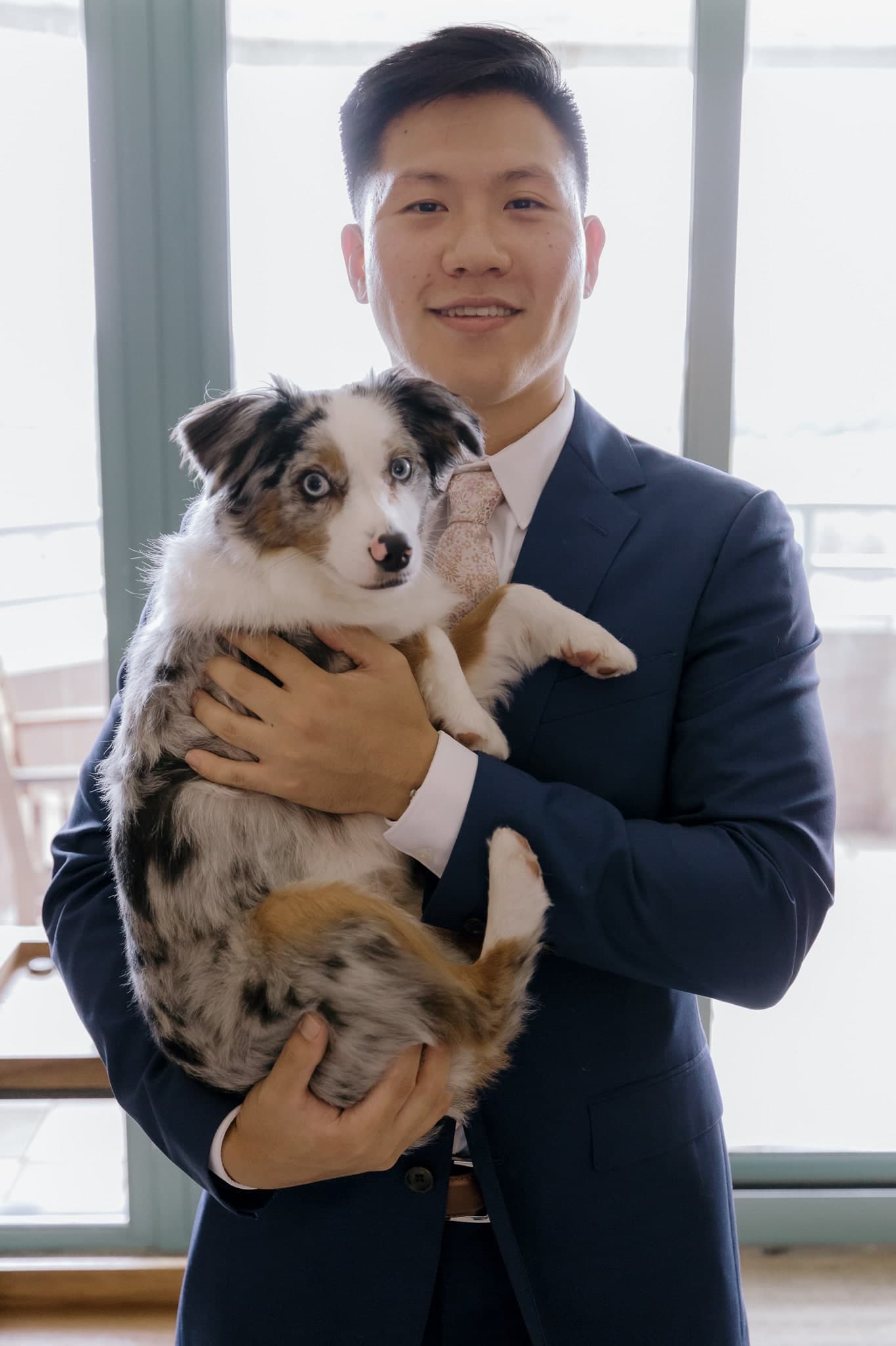 Groom holding the couple's puppy
