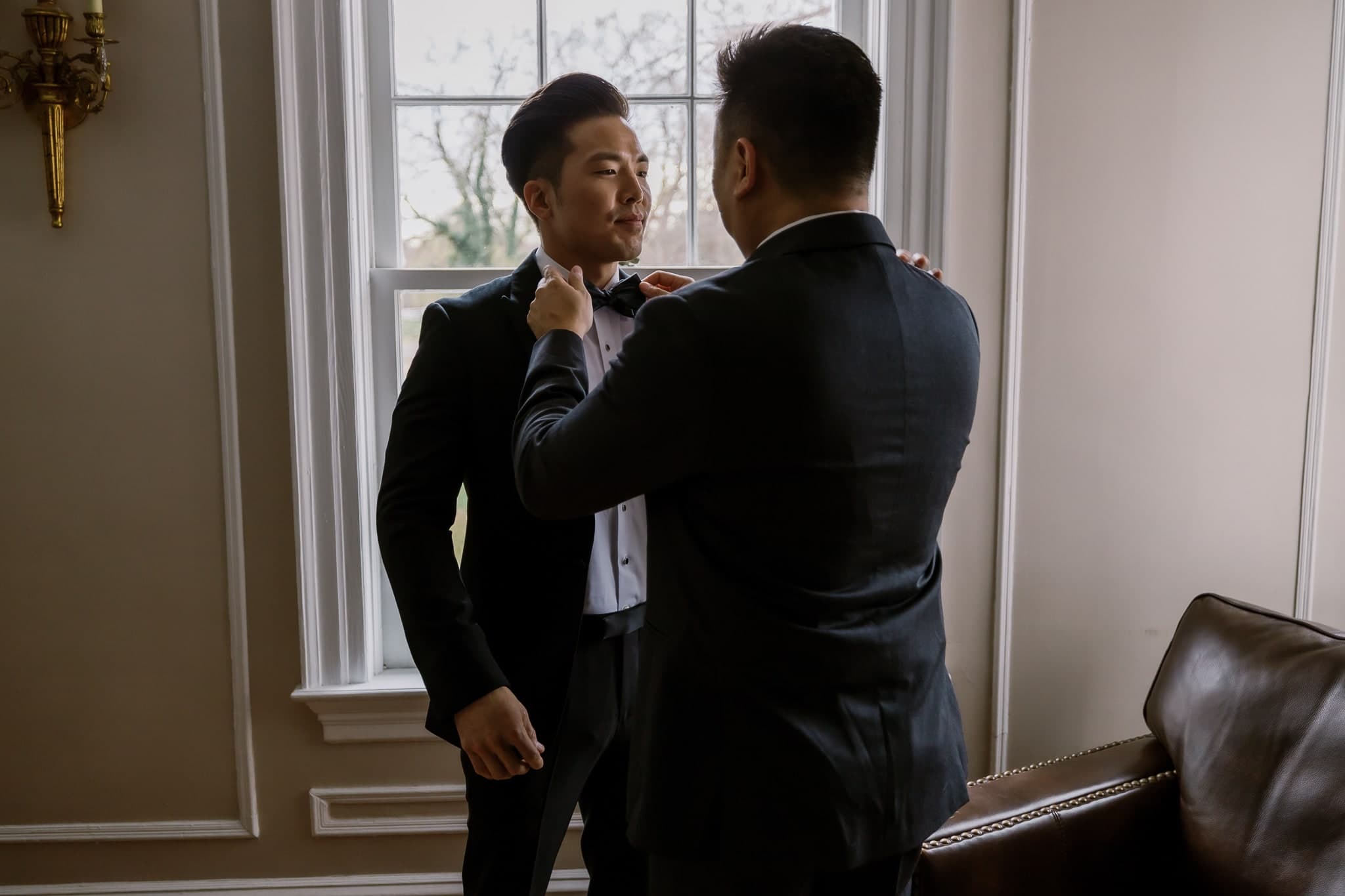Groom getting ready with help from a friend