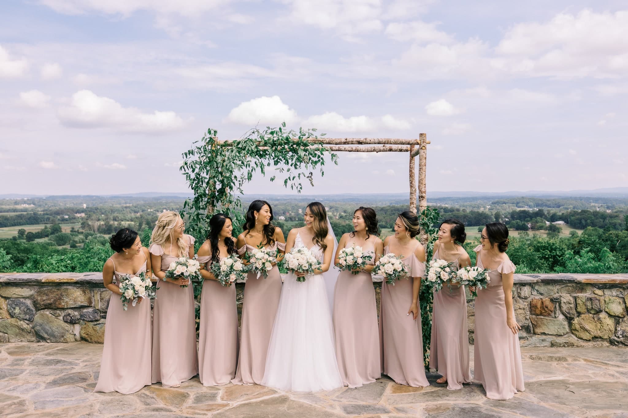 Bridesmaids at the arbor with the valley behind