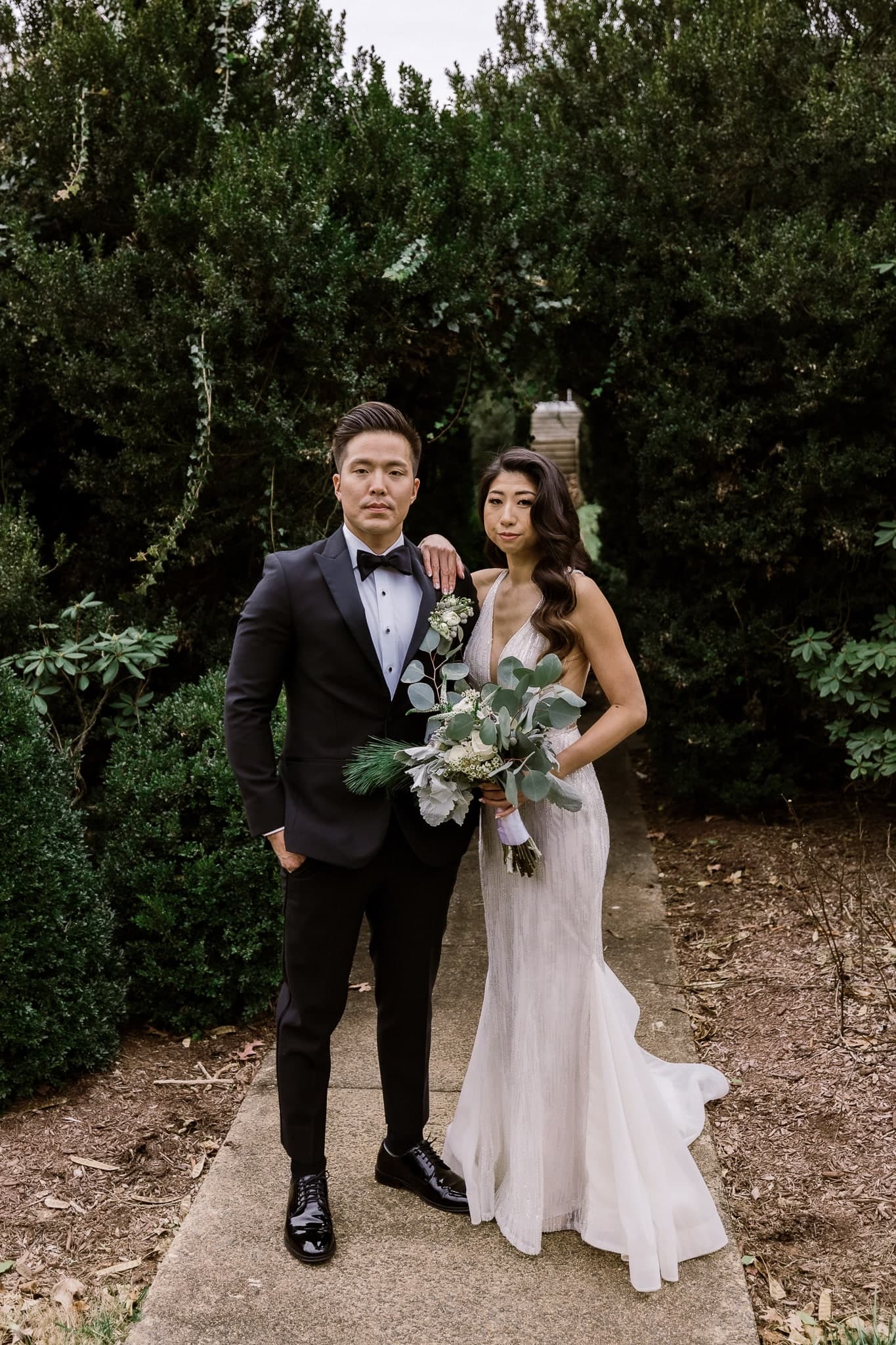 Couple on a stone path between evergreen shrubs