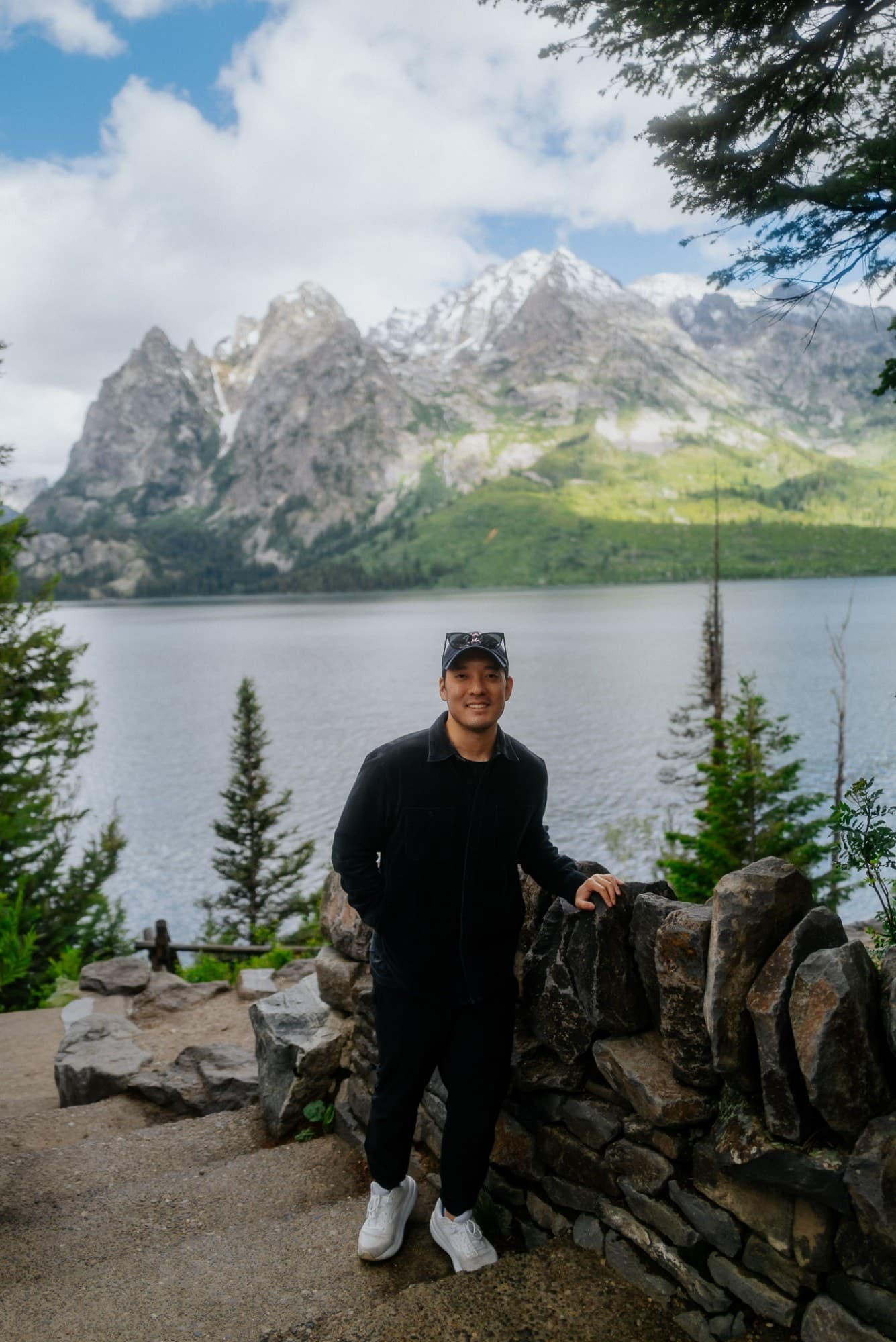 Daniel Baik at a lakeside overlook beneath snow-capped mountains