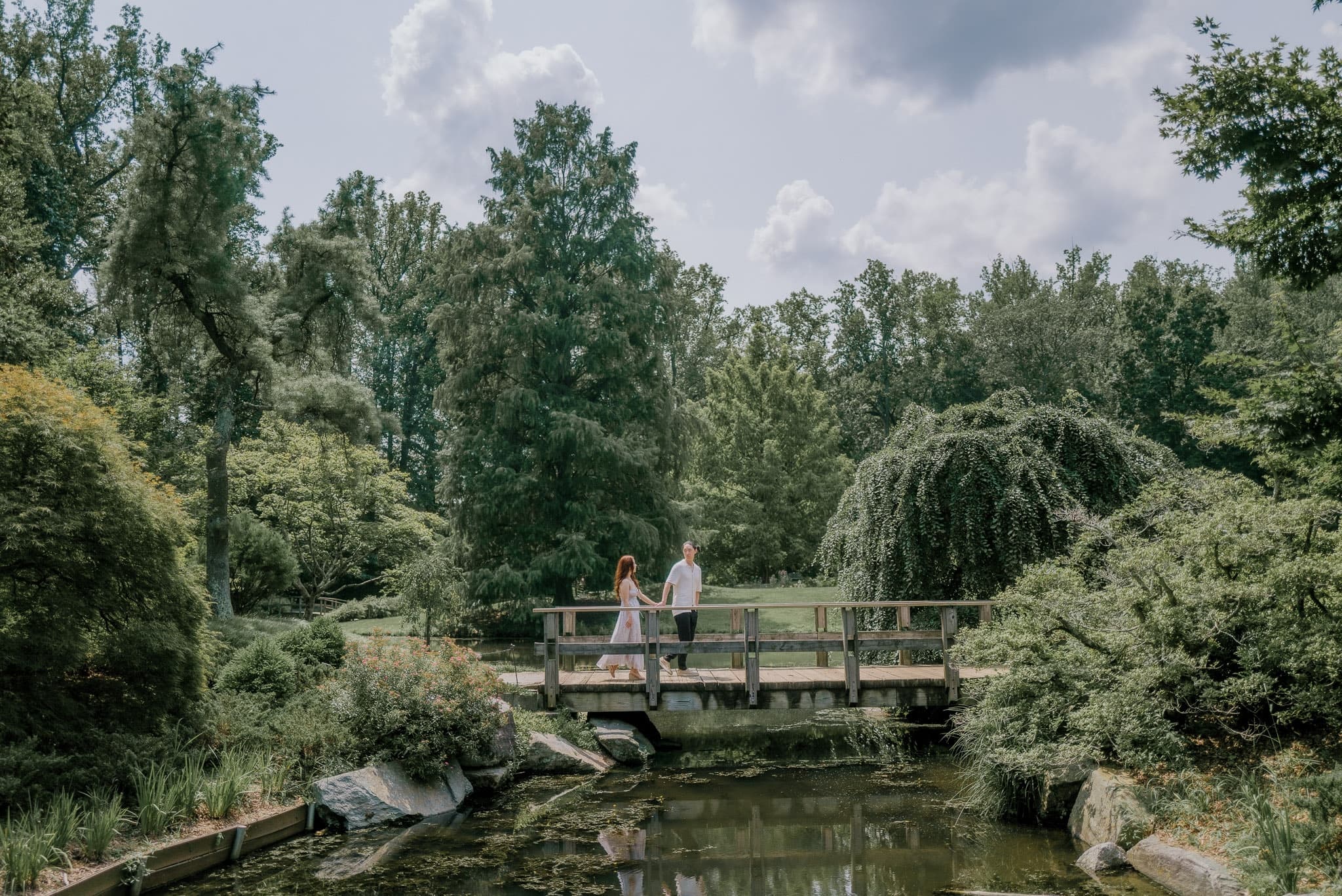 Couple on a wooden footbridge in a lush summer garden