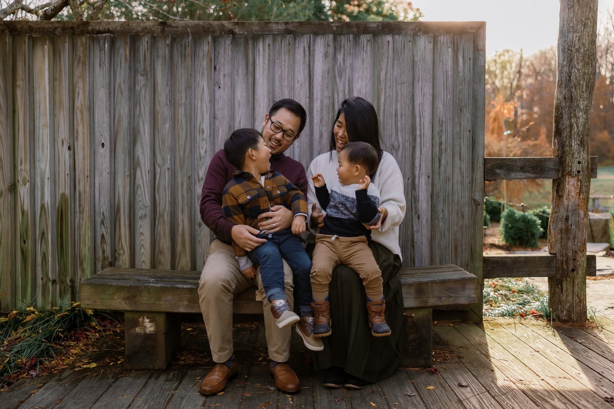Family of four laughing together on a wooden bench
